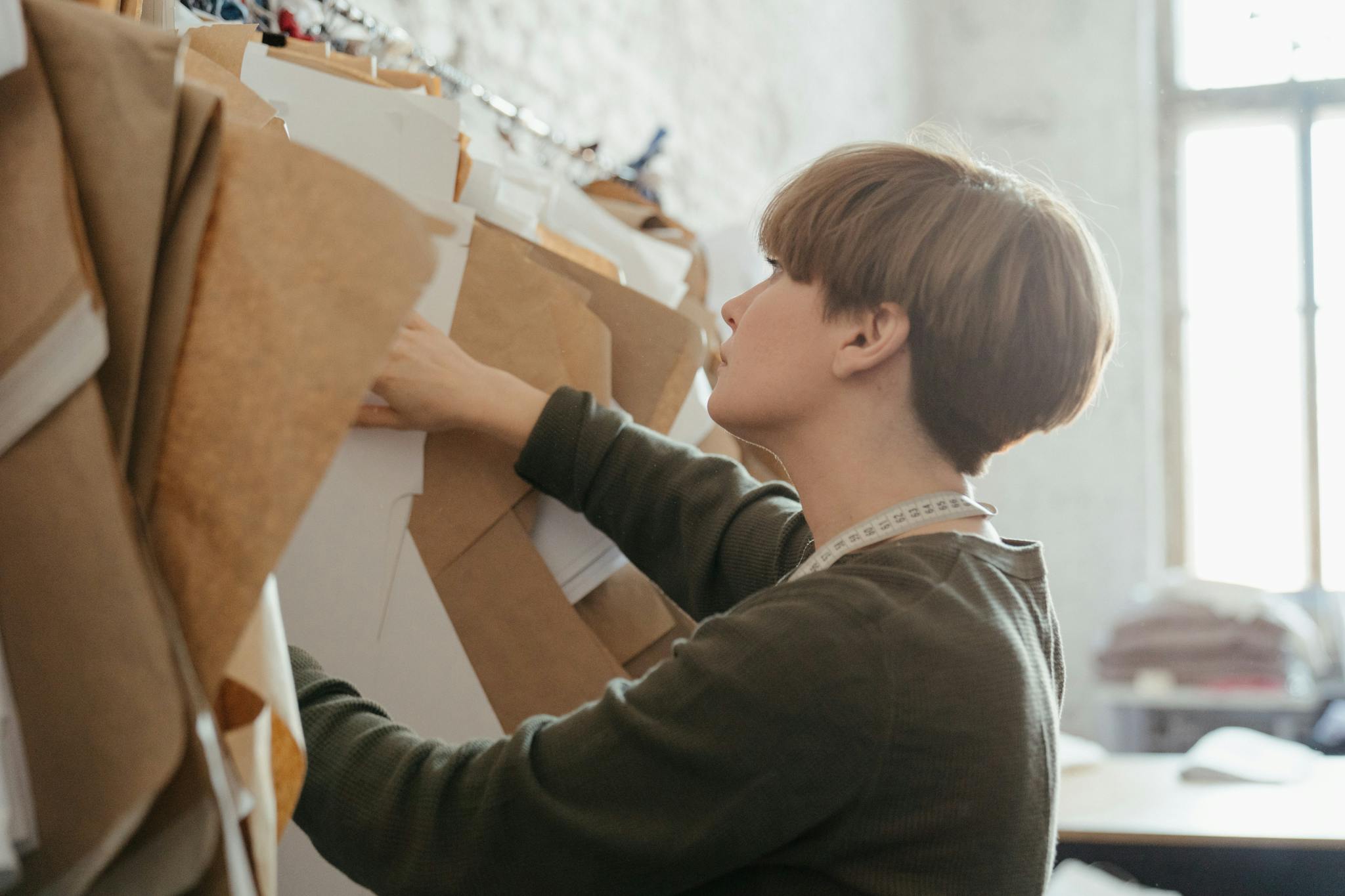A designer arranges paper patterns in a sewing studio, highlighting creativity and organization.