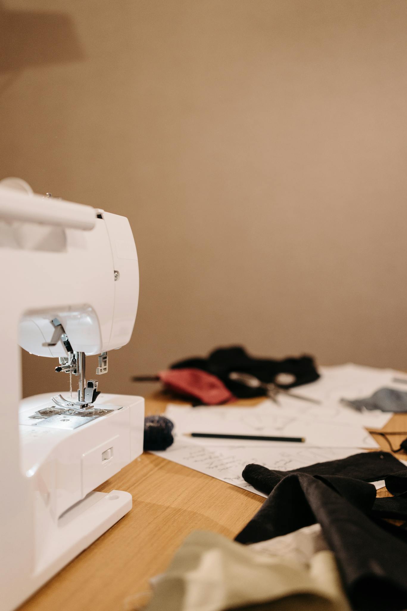 A sewing machine on a cluttered table with fabrics and tools in a small business workspace.