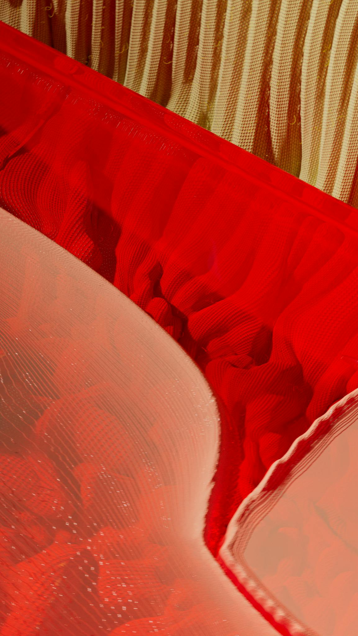Colorful abstract image featuring vibrant red textile layers and textures.