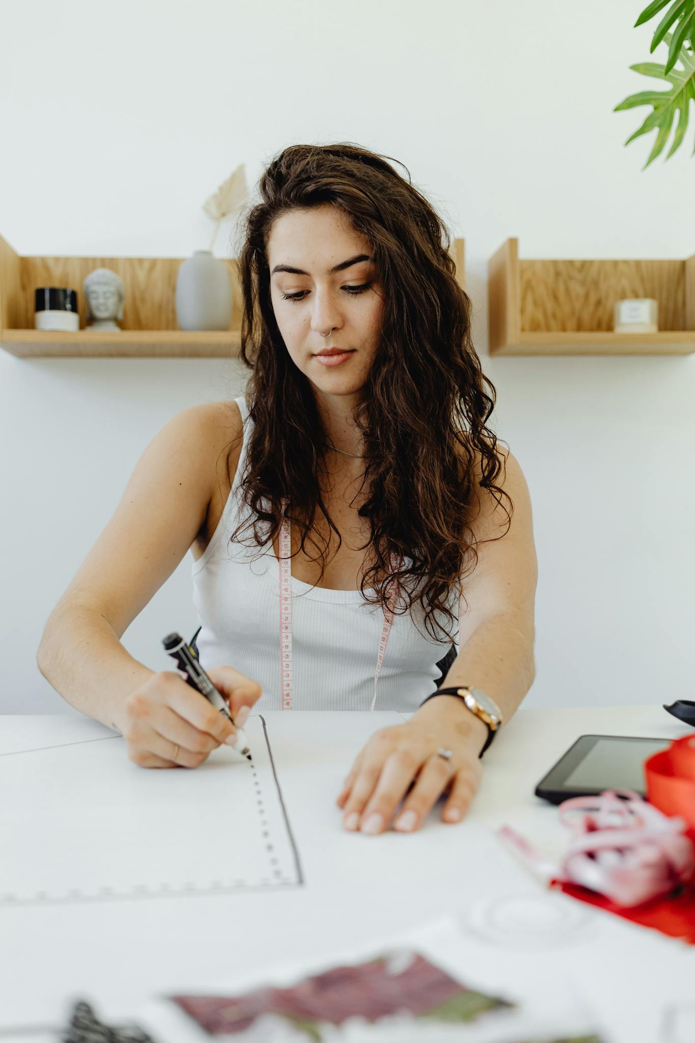 Young female fashion designer drawing new clothing patterns indoors.